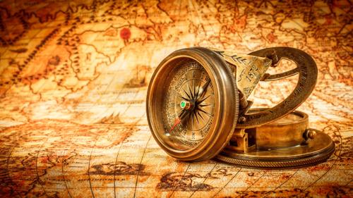 Vintage compass lies on an ancient world map.